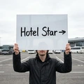 Tabliczka suchościeralna A3 z przykładowym napisem Hotel Star i strzałką trzymana przez mężczyznę na parkingu