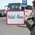 Tabliczka suchościeralna w czerwonej ramce z napisem Hotel: Abra trzymana w dłoni na dworcu autobusowym