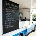 Zewnętrzna tablica kredowa z przykładowym nadrukiem menu lodziarni zamontowana na boku food trucka