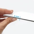 Biała płyta dibond trzymana w dłoni, prezentująca grubość materiału wynoszącą 3 mm na zbliżeniu